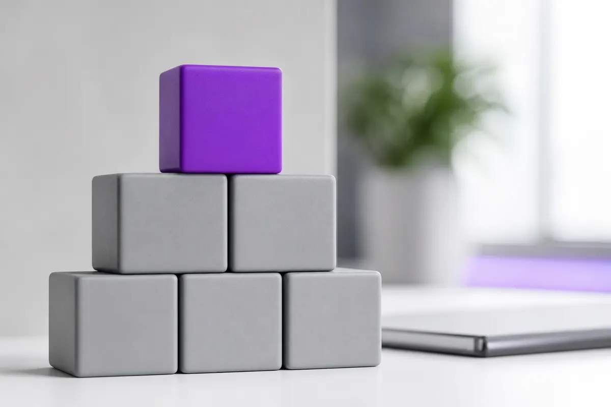 Pilha de blocos de construção cinzas organizados com um bloco roxo no topo.